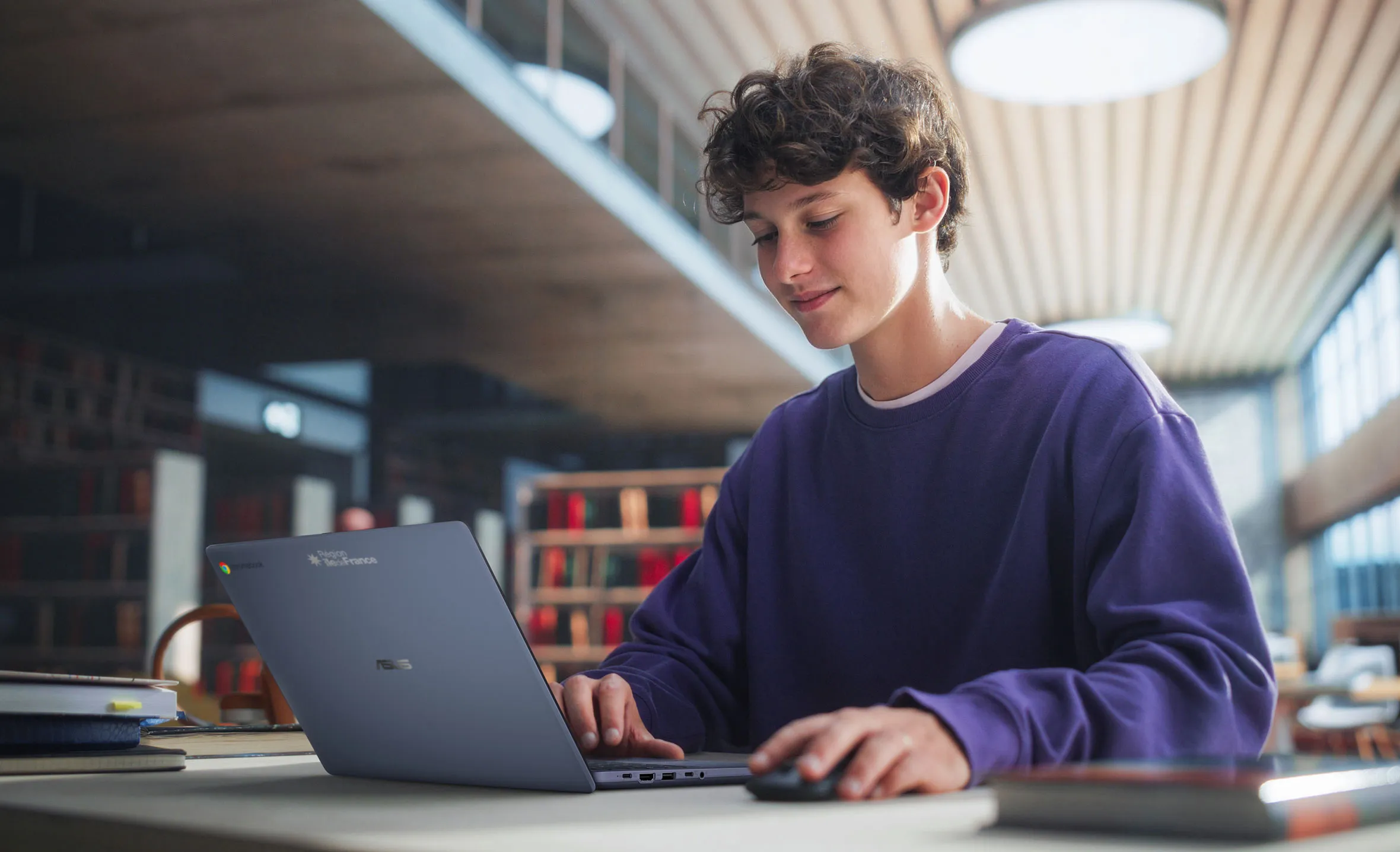 Étudiant utilisant un Chromebook Plus CX14 d'ASUS dans une bibliothèque.